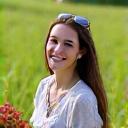 Ritratto di Anna Rossi, studentessa di botanica, con un quadernino di appunti in un campo