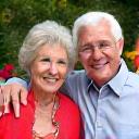 Ritratto di una coppia senior sorridente, Elena e Giorgio Ferrari, in un giardino fiorito